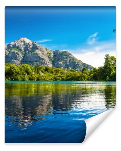 Lake with clear water green grass on the coast and reflected mountain. Argentina