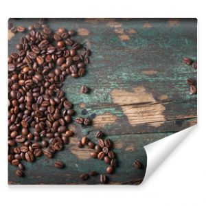 Roasted coffee beans with green leaves on a vintage background, top view with copy space