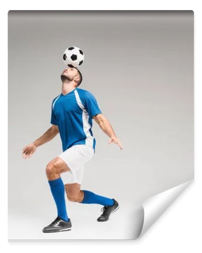 Sportsman holding football on head while balancing on grey background 