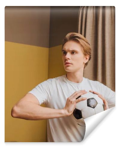 young handsome man holding football at home, end of quarantine concept