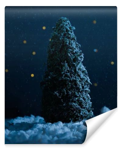 close-up shot of miniature christmas tree standing in snow in night