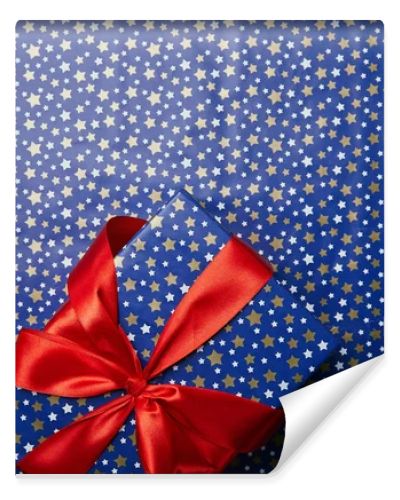 top view of wrapped gift box with red ribbon on festive wrapping paper with stars pattern