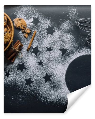 view from above of cookies in bowl, whisks and rolling pin on table covered by flour with symbol of stars