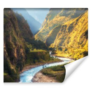 Amazing landscape with high Himalayan mountains, beautiful curving river, green forest, blue sky with clouds and yellow sunlight in autumn in Nepal. Mountain valley. Travel in Himalayas. Nature