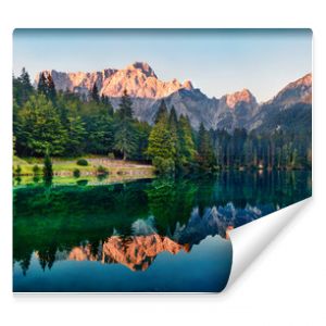 Calm morning view of Fusine lake. Colorful summer sunrise in Julian Alps with Mangart peak on background, Province of Udine, Italy, Europe. Beauty of nature concept background.