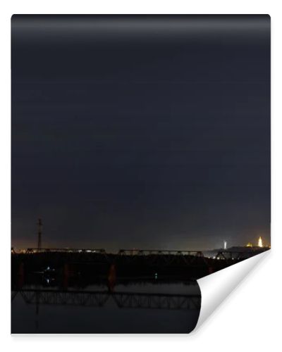 dark cityscape with tranquil river and bridge at night