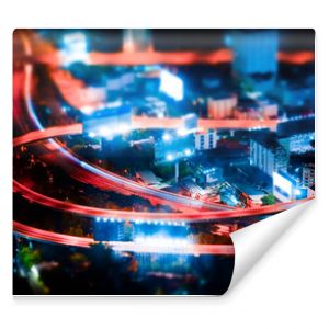 Tilt shift blur effect. Futuristic night cityscape aerial view panorama with illuminated skyscrapers and city traffic across streets. Bangkok, Thailand
