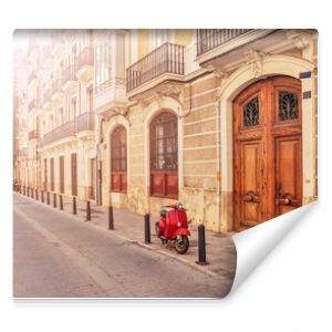 Spain. Valencia. A street in the tourist city of Valencia. Red motorcycle, moped. Tourist concept. Journey. Red vintage scooter parked on a sidewalk.