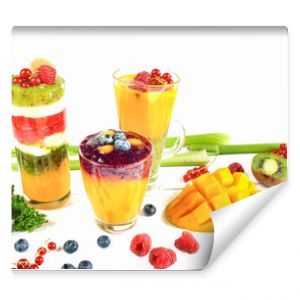 Wielowarstwowe smoothie w szklankach wokół rozsypanych owoców