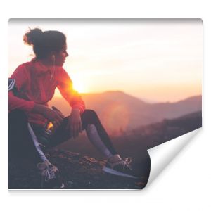 Wysportowana kobieta odpoczywa po ciężkim treningu w górach o zachodzie słońca Obcisłe ubrania sportowe