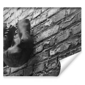 Old boxing gloves hang on nail on brick wall with copy space for text. High resolution 3d render