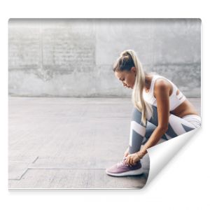 Kobieta uprawiająca sport fitness w modnej odzieży sportowej ćwicząca na szarej ścianie