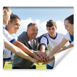 Team of young football players stacking hands before match