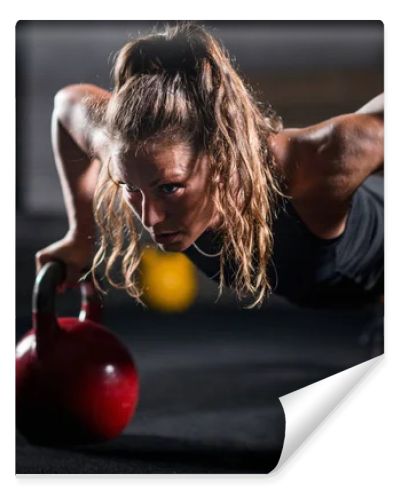 Woman athlete exercising with kettlebells indoors