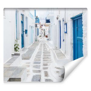 Mykonos Grecja Tradycyjna bielona ulica miasta Mykonos z niebieskimi oknami i drzwiami w słoneczny letni poranek Pusta uliczka