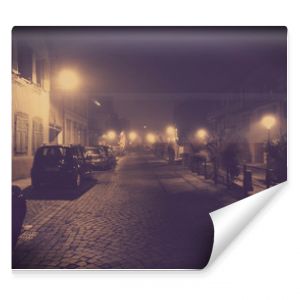 Foggy street of the old city with cars. ancient cobbled street and a blurred light of the street lamps