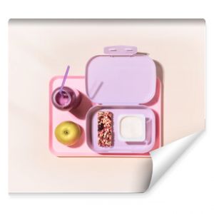 The concept of healthy school meals. Food composition with lunch box with yogurt, cereal bar, apple and oatmeal berries cocktail on a pink background with window light. Flat lay, horizontal banner