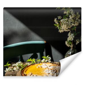 Freshly baked homemade lemon pie with floral crust decorations  in baking form, lemons and cherry blossom  on old wooden table on dark background. 