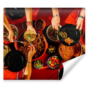 Overhead shot of a dinner table with Mexican food and hands. Tacos, beans, carnitas, habanero, salsa