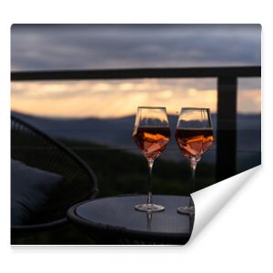 Two glasses of wine standing with a beautiful scenic mountain view. Mountain resort, enjoy moment