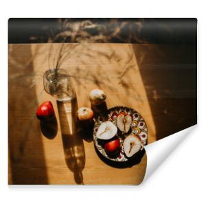 still life with a bottle. pears on a wooden table. pears on a wooden table bathed in the sun. picnic in the summer garden. flowers and fruits on a wooden table. sunny shadows on the kitchen table