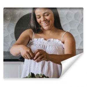 Young adult woman preparing salad for lunch in luxury kitchen