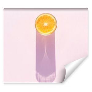 Glass of drink with orange on a pink background. Aesthetic long shadow glass summer concept.