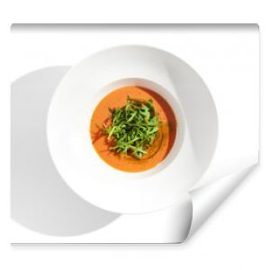 Summer Spanish soup - gazpacho with rocket salad isolated on white background. Vegetarian cold tomato soup in white plate. Meatless food in menu. Veggie lunch. Healthy food. Plant based eating.