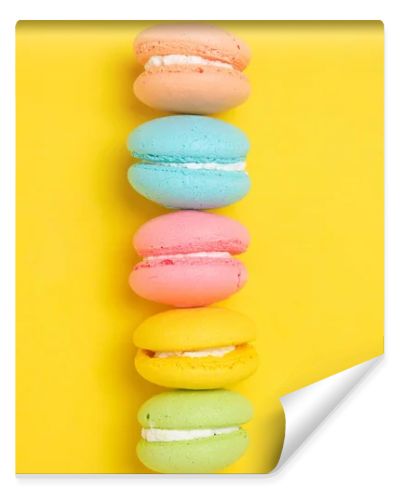 Colorful and bright French macarons cookies on yellow background