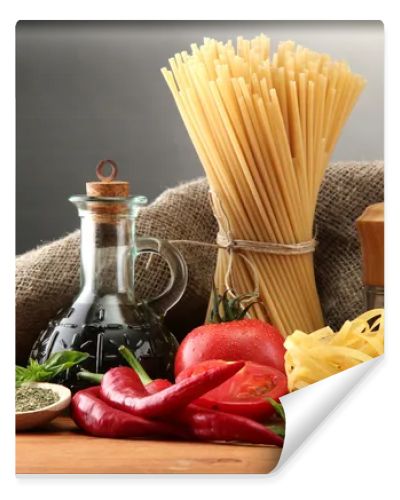 Pasta spaghetti, vegetables and spices, on wooden table, on grey background