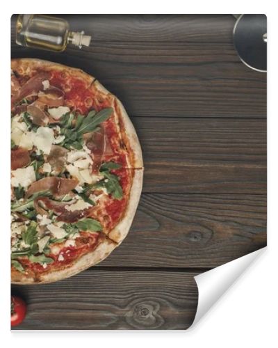 flat lay with arranged italian pizza, cutlery and various ingredients on wooden surface