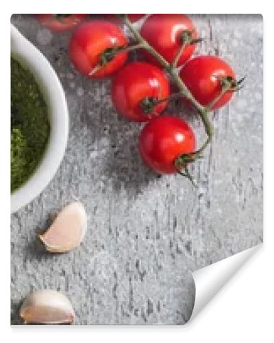 top view of raw tomatoes, garlic, basil, pine nuts, olive oil, pesto sauce on grey surface, panoramic shot