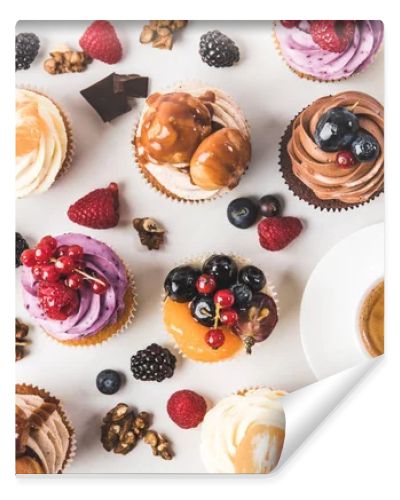 flat lay with cup of coffee, sweet cupcakes, berries, chocolate pieces and hazelnuts isolated on white