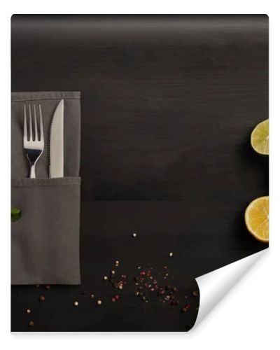 flat lay with cutlery, sauce, rosemary, spices and citrus fruits pieces on black tabletop