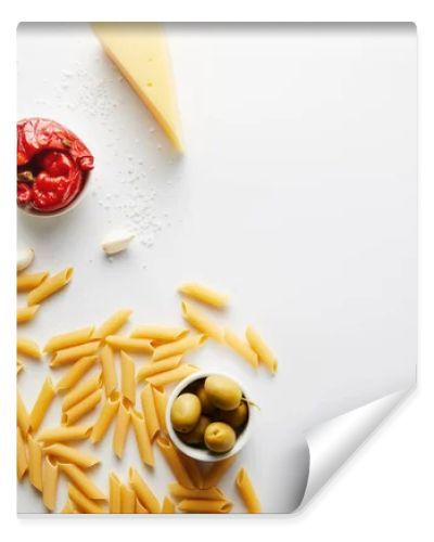 Top view of bottle of olive oil, pasta, cheese and ingredients on white background 