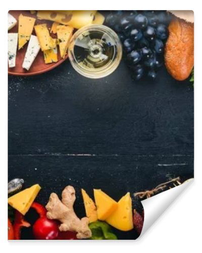 Assorted cheeses, sausages, wines, traditional spices and fresh vegetables on a wooden background. Cheese brie, blue cheese, gorgonzola, fuete, salami. Italian and Spanish Cuisine. Free space.
