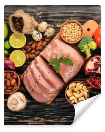 Healthy food. Raw meat, avocado, broccoli, fresh vegetables, nuts and fruits. On a wooden background. Top view. Copy space.