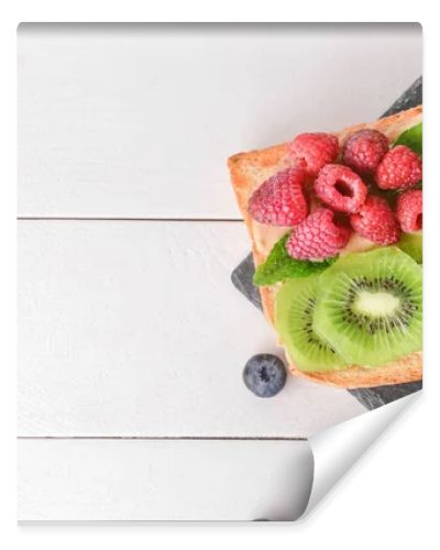 Slate plate with tasty sandwiches, kiwi and berries on white table