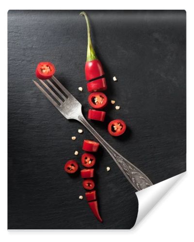 elevated view of cut red ripe chili pepper and fork on black surface