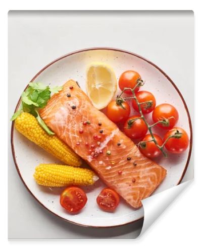 top view of raw salmon steak served with corn and tomatoes on plate near cutlery on marble table