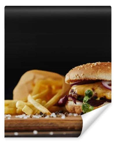 salt, french fries and delicious burger with meat on wooden surface isolated on black