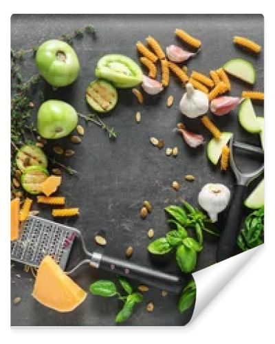 Dry pasta, grater, cheese and vegetables on grey background