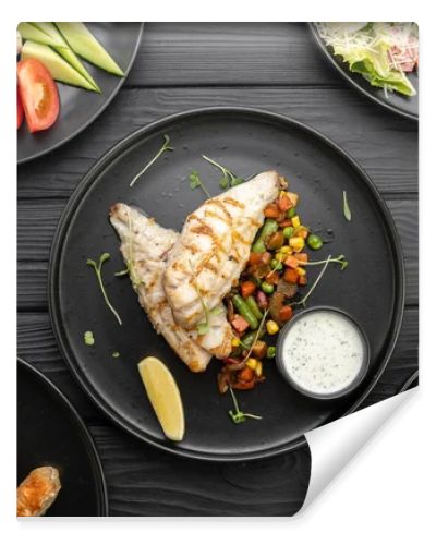 Top view of various grilled dishes served on a dark table in a restaurant. Fish fillet with vegetables. Flat lay