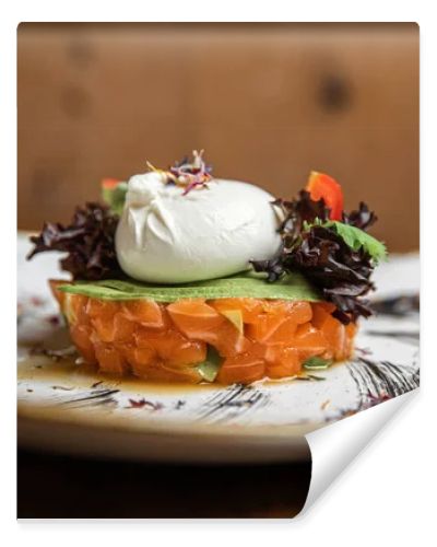 Raw salmon, avocado purple onion salad served in culinary ring on black plate. Wooden background