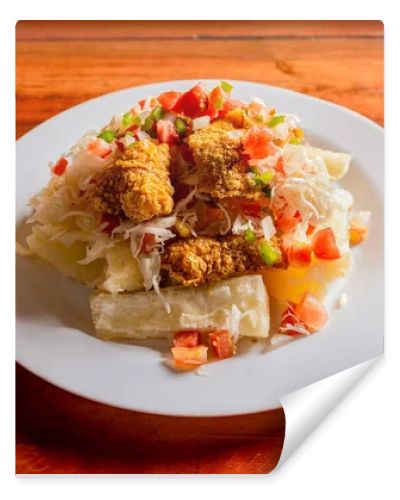 Traditional chicharron dish with cassava and tomato salad. Latin food chicharron con yuca served on wooden table. Nicaraguan dish chicharron with cassava on the table.