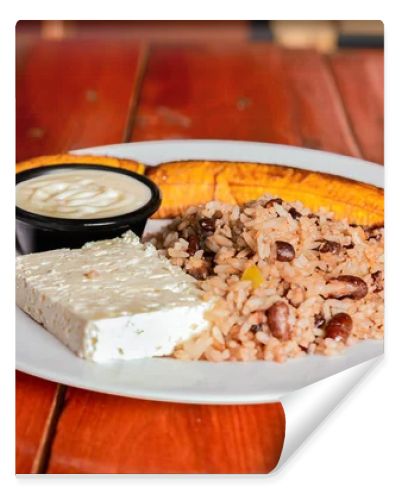 Traditional Gallo Pinto meal with maduro and cheese served. Gallopinto plate with cheese and maduro on wooden table. Nicaraguan food concept