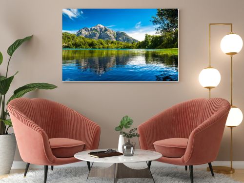 Lake with clear water green grass on the coast and reflected mountain. Argentina