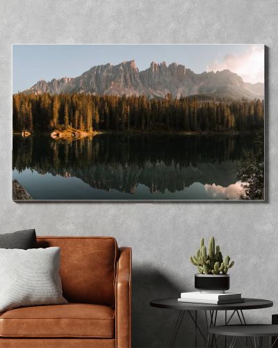 A scenic view of a calm lake with the reflection of trees and the Dolomites Mountains in Italy