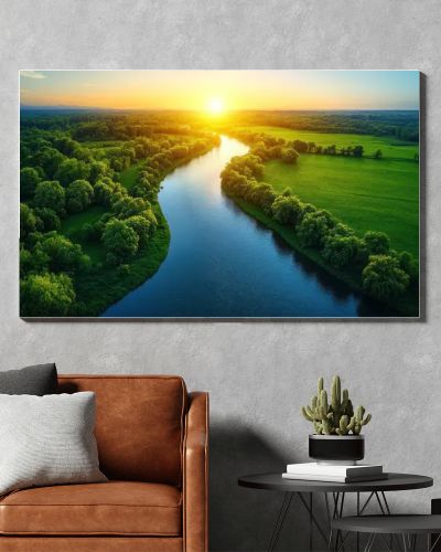 Aerial view of a river flowing through lush green fields at sunset.