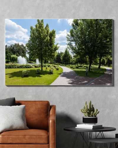 panoramic shot of green trees on grass near fountains